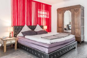 a bedroom with a large bed with red curtains at Sandkorn-Büsum in Büsum