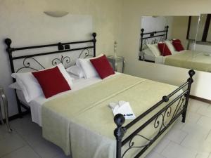 ペスキエーラ・ボッロメーオにあるHotel Motel Estのベッドルーム1室(赤い枕と鏡付きのベッド2台付)