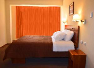 a bed in a hotel room with an orange window at Illariy Hotel in Huancavelica