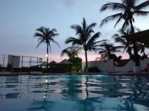 una piscina al crepuscolo con palme sullo sfondo di Hotel QUINTA DIAMANTE a Barra Vieja