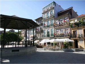 duży budynek ze stołami i parasolami przed nim w obiekcie Caldeira Guest House w Porto
