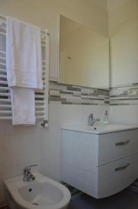 a white bathroom with a sink and a mirror at La Collinetta Dei Sassi in Matera