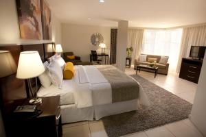 Hotel Los Andes في سان بيدرو سولا: غرفة نوم بسرير كبير وغرفة معيشة
