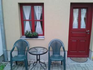 zwei Stühle und ein Tisch vor einer roten Tür in der Unterkunft Apartman Lidicka in Marienbad