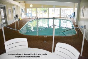 a swimming pool in a building with chairs around it at Neptune Motel Maine in Old Orchard Beach