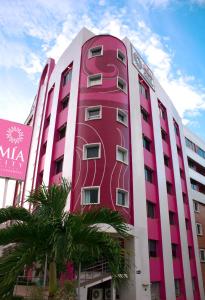a pink building with palm trees in front of it at Mia City Villahermosa in Villahermosa