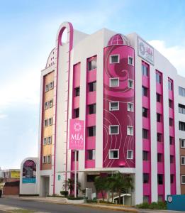 比亞埃爾莫薩的住宿－Mia City Villahermosa，粉红色和白色的建筑,上面有标志
