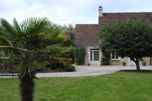 a house with a palm tree in front of a yard at Chambres d'Hotes Elvire et Laurent Barbey in Sainte-Marie-du-Mont