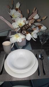 a table with a white plate and a vase of flowers at Apartament Magnolia przy morzu in Międzyzdroje