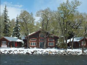a log cabin in the snow next to a river at Riverside Meadows Cabins in South Fork