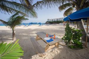 
a beach area with chairs, tables, and umbrellas at El Zafiro Boutique Hotel in Maho Reef
