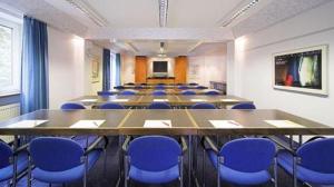 a conference room with a long table and blue chairs at Main Hotel Eckert 3-Sterne Superior in Margetshöchheim