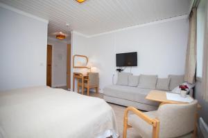 a white bedroom with a bed and a couch at Stetind Hotel in Kjøpsvik