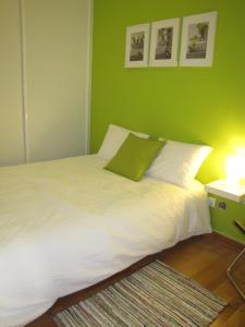 リスボンにあるAppartement calme / Alfamaの緑の壁のベッドルーム1室(白いベッド1台付)