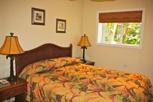 a bedroom with a bed and two lamps and a window at Maui Beach House B & B in Kahana