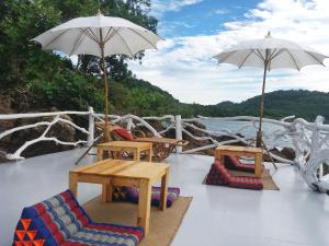 um deque com cadeiras, mesas e guarda-sóis num barco em Rock View Terrace em Ko Jum