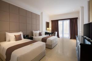 a hotel room with two beds and a flat screen tv at Grand Palace Hotel Sanur - Bali in Sanur