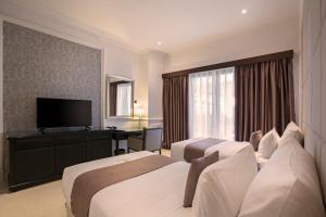 a hotel room with two beds and a television at Grand Palace Hotel Sanur - Bali in Sanur