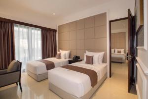 a hotel room with two beds and a window at Grand Palace Hotel Sanur - Bali in Sanur