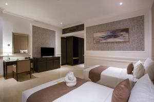 a hotel room with two beds and a desk at Grand Palace Hotel Sanur - Bali in Sanur