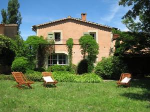 three chairs sitting in the grass in front of a house at Domaine de la Bastidonne in Céreste