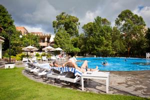a group of people laying on lounge chairs by a pool at Park Village Resort by KGH Group in Kathmandu