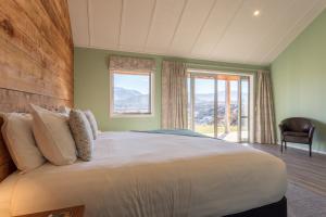 a bedroom with a large bed and a large window at Shotover Country Cottages in Queenstown