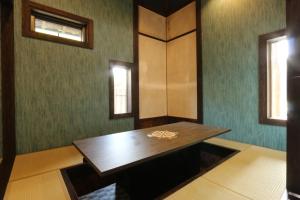 a room with a wooden table and two windows at Minshuku Asogen in Aso