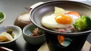 a cup of food with an egg and broccoli on a table at Minshuku Asogen in Aso