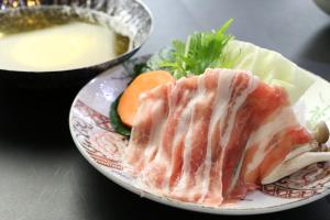 a plate of food with meat and a bowl of soup at Minshuku Asogen in Aso
