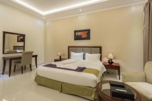 a bedroom with a bed and a table and a desk at Taleen Serviced Apartments Al Nakheel in Riyadh