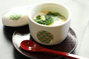 a cup of soup on a plate with a red spoon at Minshuku Asogen in Aso