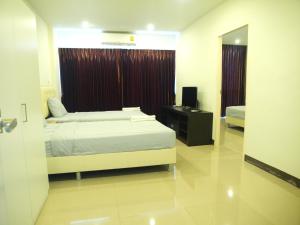1 dormitorio con cama, TV y espejo en BB Grand Residence, en Pattaya central