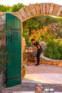 Eine Frau, die an einem Tisch im Garten steht. in der Unterkunft I Dammusi di Borgo Cala Creta in Lampedusa