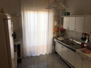 カラベルナルドにあるCasa vacanze Maria Graziaのキッチン(シンク付)、窓(カーテン付)