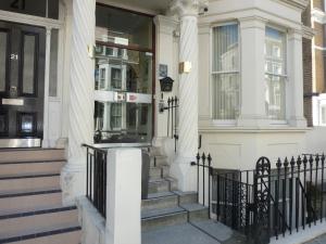 a white house with a front door and stairs at Manor Hotel in London