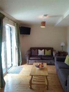 ein Wohnzimmer mit einem Sofa und einem Tisch mit einer Obstschale in der Unterkunft Delphi Cottage in Ashbourne