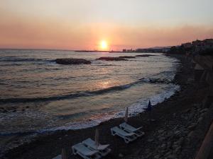 - deux chaises longues sur une plage au coucher du soleil dans l'établissement Residence Tre Palme, à Acciaroli