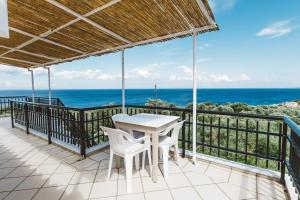 uma varanda com uma mesa e cadeiras e o oceano em Fexulis Studios & Suites em Ágios Nikolaos