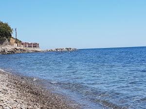 a beach with blue water and a rocky shore at Residence Tre Palme in Acciaroli