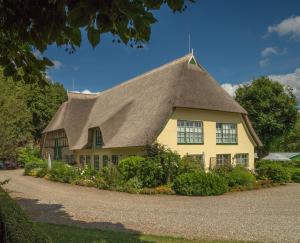 ein gelbes Haus mit einem Strohdach in der Unterkunft Hof Brooks in Bosau