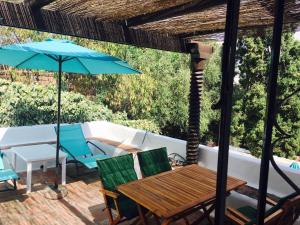 a patio with a table and chairs and an umbrella at Chalecito en la Herradura- Casa Kwetu in La Herradura