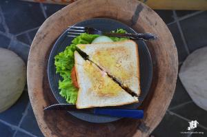 a sandwich and salad on a plate with a fork and knife at Rumah Gandrung in Yogyakarta