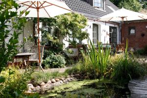 a garden with an umbrella and a table and chairs at Ferienwohnung Suederbootfahrt - Ruheoase für Naturliebhaber in Katingsiel zwischen Tönning und St Peter Ording perfekt für Radtouren in Katingsiel