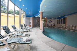 a pool with chaise lounge chairs and a swimming pool at Hotel Centro Benessere Gardel in Arta Terme
