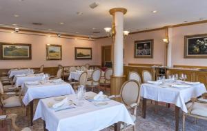 une salle à manger avec des tables et des chaises blanches dans l'établissement Hotel Riu Fluviá, à Olot