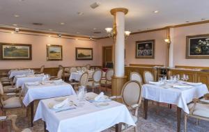 un comedor con mesas y sillas blancas en Hotel Riu Fluviá, en Olot