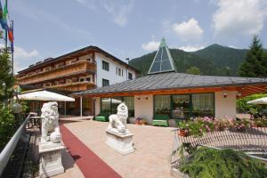 a building with a courtyard with statues in front of it at Hotel Centro Benessere Gardel in Arta Terme