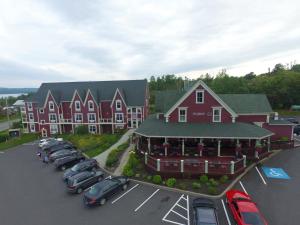 ein großes rotes Gebäude mit Autos auf einem Parkplatz in der Unterkunft Lynwood Inn in Baddeck