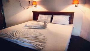 białe łóżko z białą pościelą i poduszkami w obiekcie Pepper Hills Cottages w mieście Ella